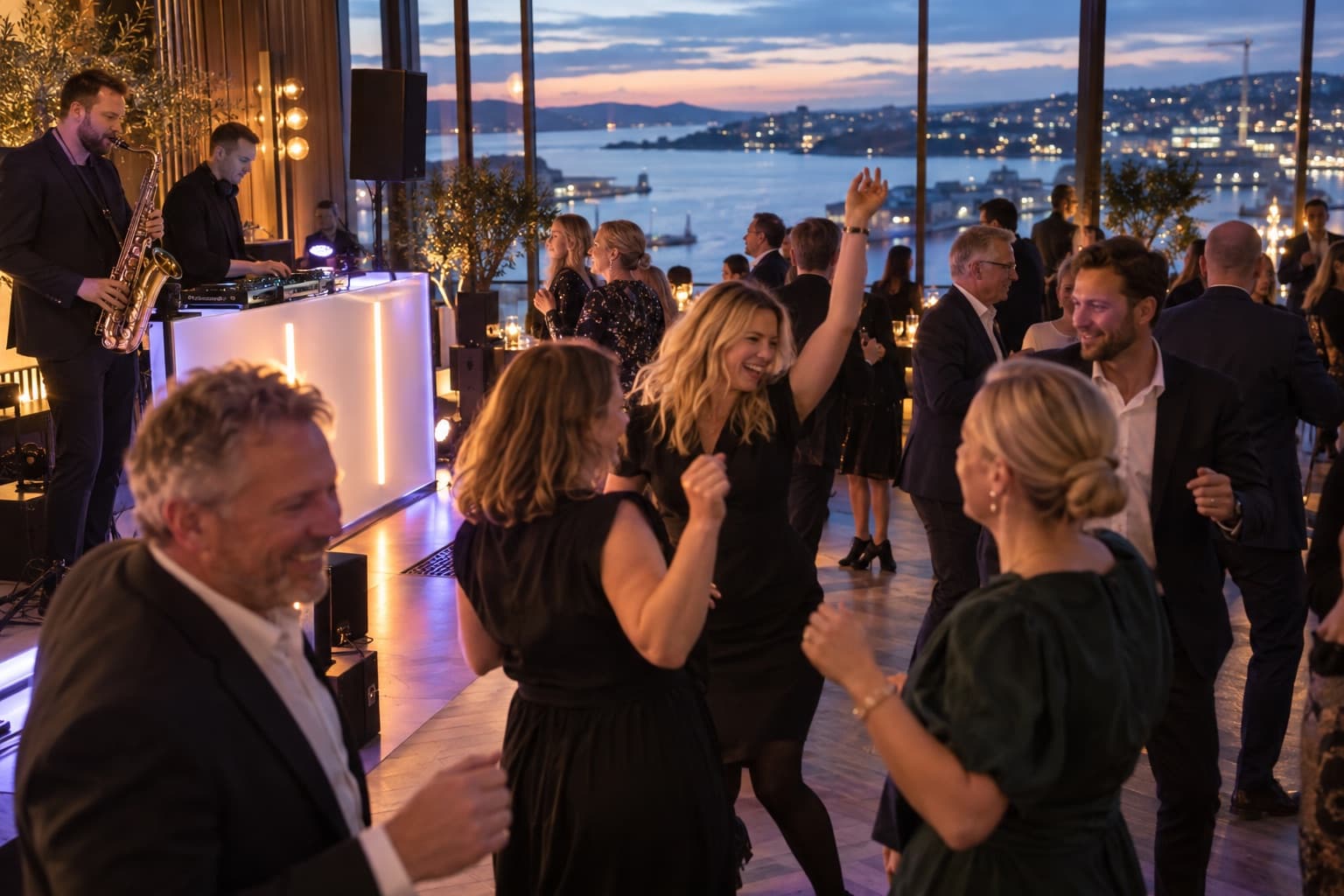 Kolleger danser foran DJ og saksofonist på firmafest i Oslo, med fjorden i vinduene